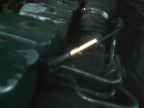 1989 Ford Bronco - Close-up view of an engine bay, showing a dipstick and a hose with a clamp.