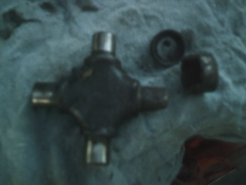 1989 Ford Bronco - A universal joint and its associated bearing caps are laid out on a textured surface.