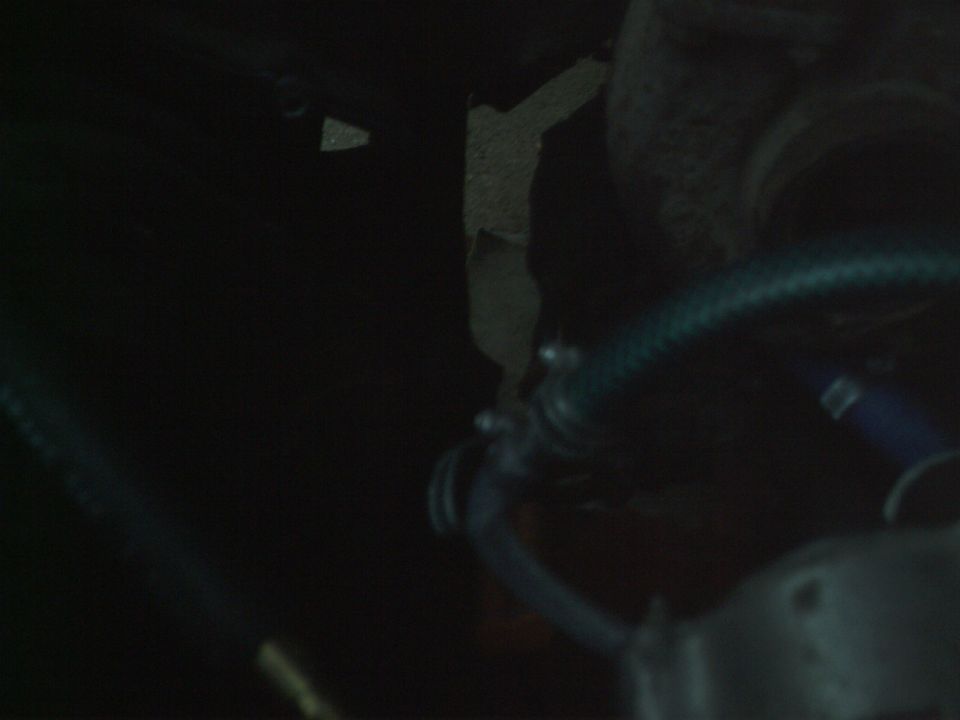 Engine bay with hoses and clamps visible, dark lighting