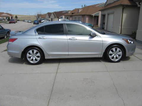 2009 Honda Accord - A silver sedan is parked on a concrete driveway in front of residential buildings.