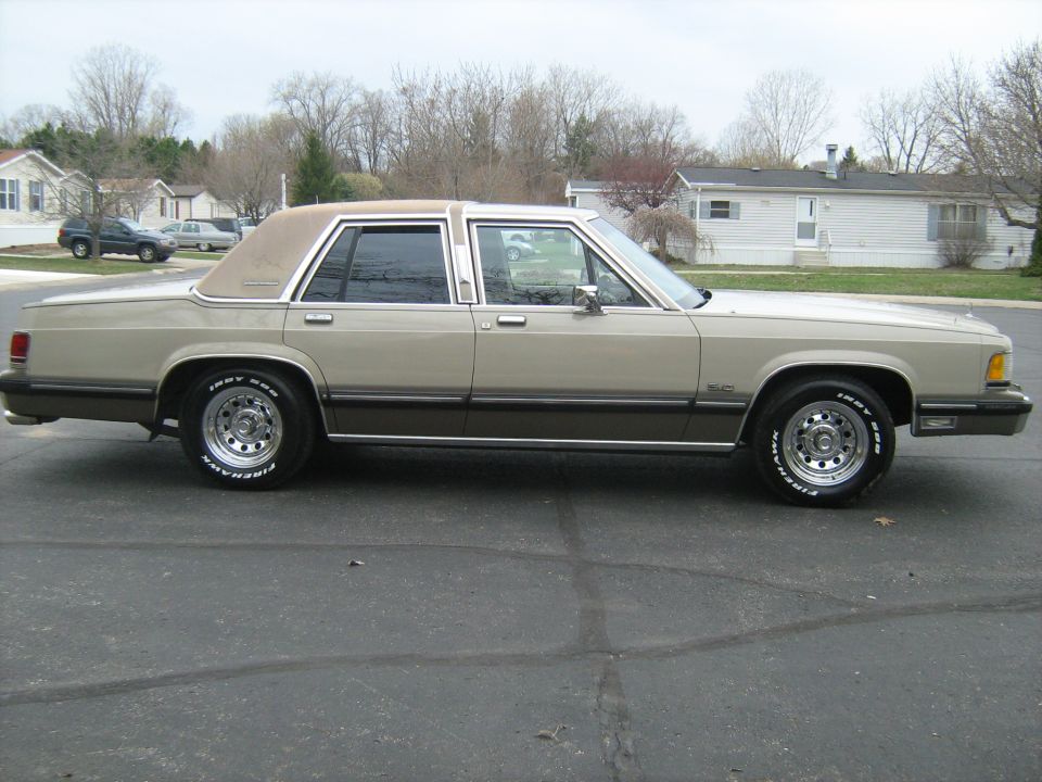 Tan 1988 Mercury Grand Marquis sedan with a brown lower body stripe and chrome wheels, seen from the side