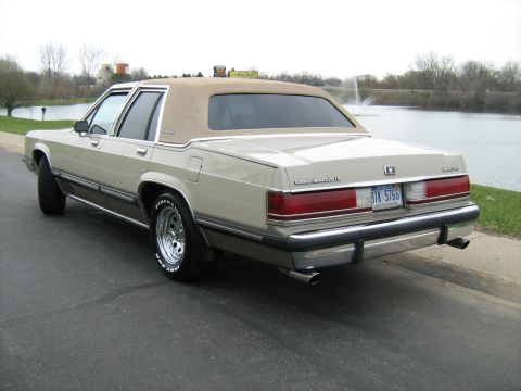 1988 Mercury Grand Marquis - This 1988 Mercury Grand Marquis features a tan exterior and a contrasting vinyl roof, seen from the rear.
