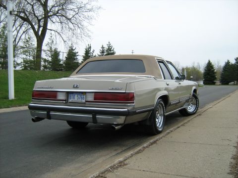 1988 Mercury Grand Marquis - Rear view of a 1988 Mercury Grand Marquis with a tan vinyl roof and chrome wheels.