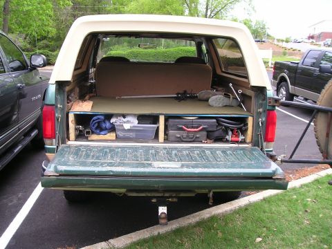 1989 Ford Bronco - Rear view of a green Ford Bronco showing its custom storage setup and contents.
