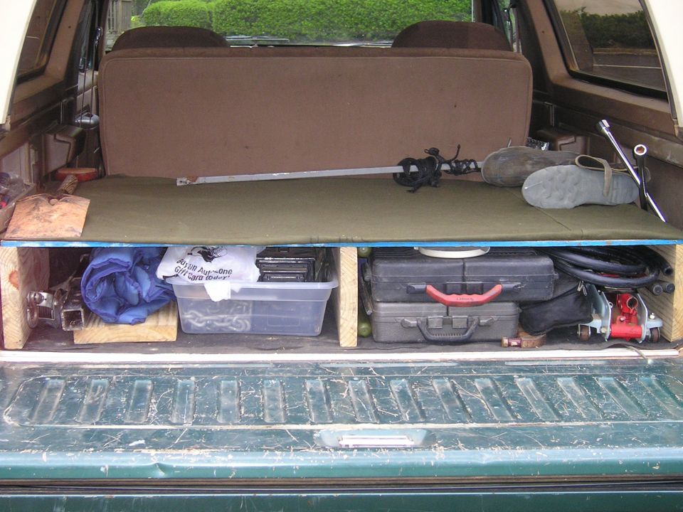 Vehicle cargo area with storage bins, tools, and a sword