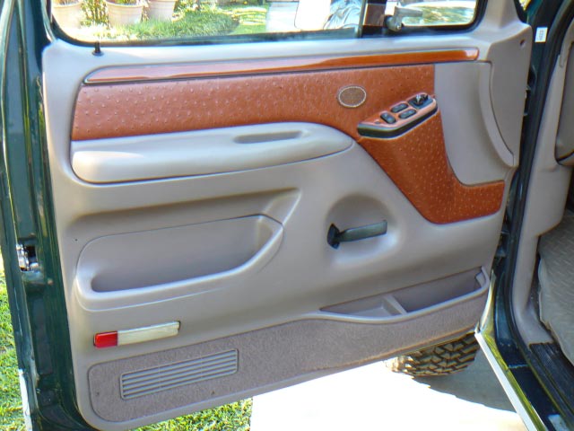 Driver's side door panel with tan and orange textured trim, power window controls, and storage pockets