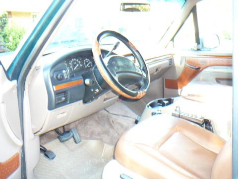1992 Ford Bronco - The interior of a 1992 Ford Bronco features tan leather seats, a wood-trimmed steering wheel, and a dashboard with visible gauges.