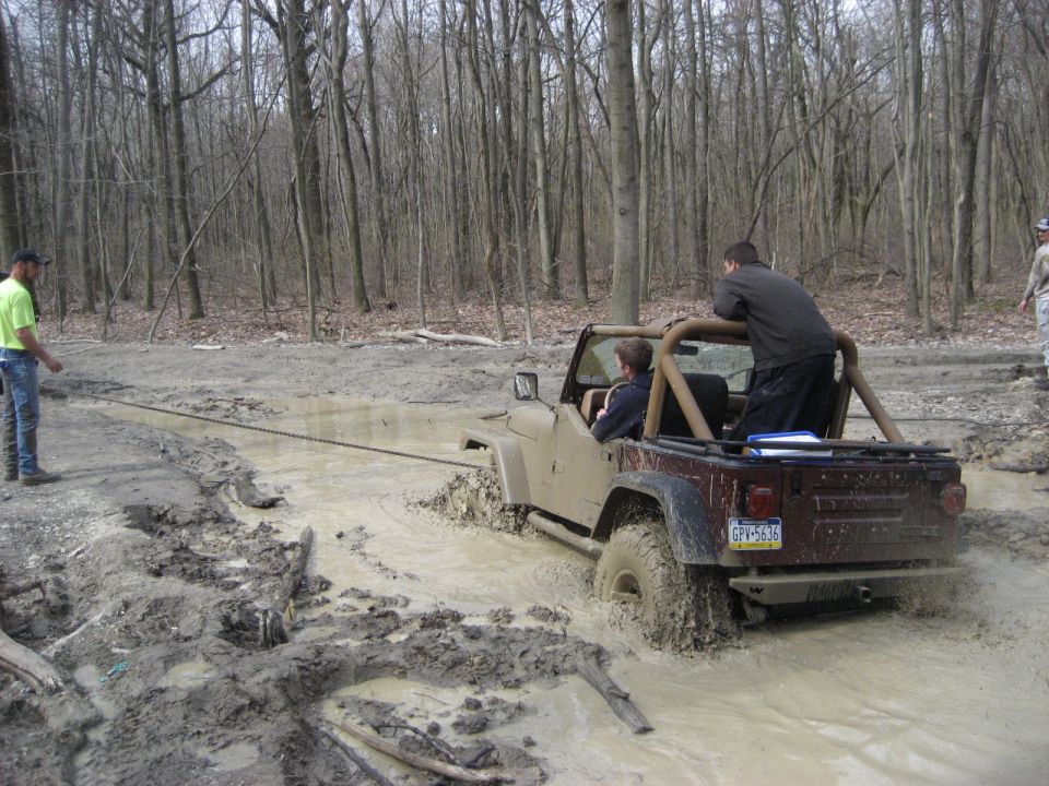 Tan Jeep Wrangler stuck in mud, rear view