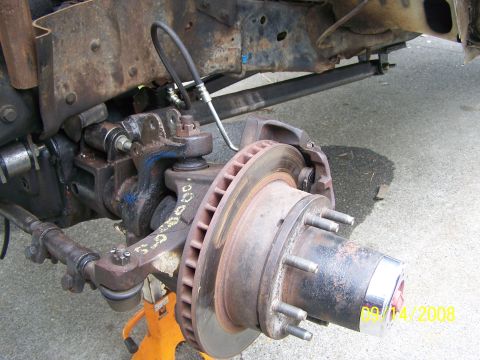1982 Ford Bronco - Close-up of a vehicle's front suspension components, including a brake rotor and hub assembly.