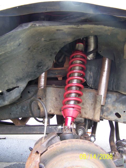 1982 Ford Bronco - The photo shows a close-up of a vehicle's front suspension system, focusing on a red shock absorber.