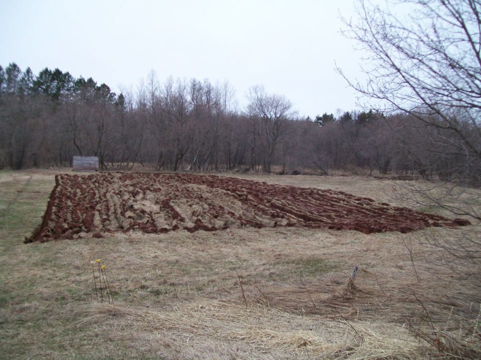 Plowed field with a shed and trees
