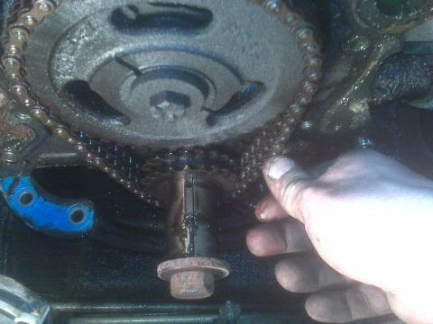 1995 Ford Bronco - A hand is shown near the timing chain and gears of an engine, likely during maintenance or repair.
