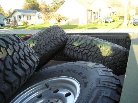 1997 Ford F-250 - Several large off-road tires are loaded into the bed of a pickup truck.
