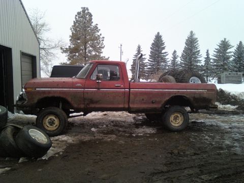 1978 Ford F-150 - Side view of a red 1978 Ford F-150 pickup truck with a lifted suspension and large exhaust pipe.
