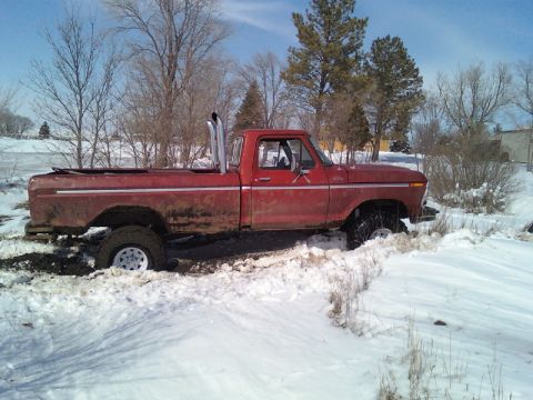 1978 Ford F-150 - A red 1978 Ford F-150 pickup truck is stuck in the snow with its tires partially submerged.