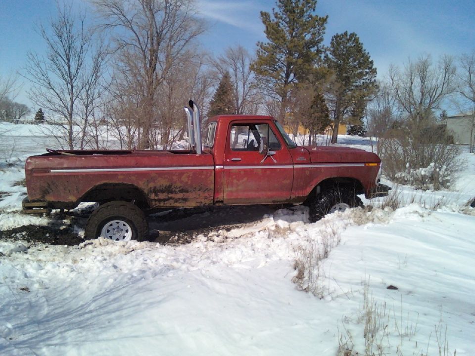 Red 1978 Ford F-150 stuck in snow with tall exhaust pipes