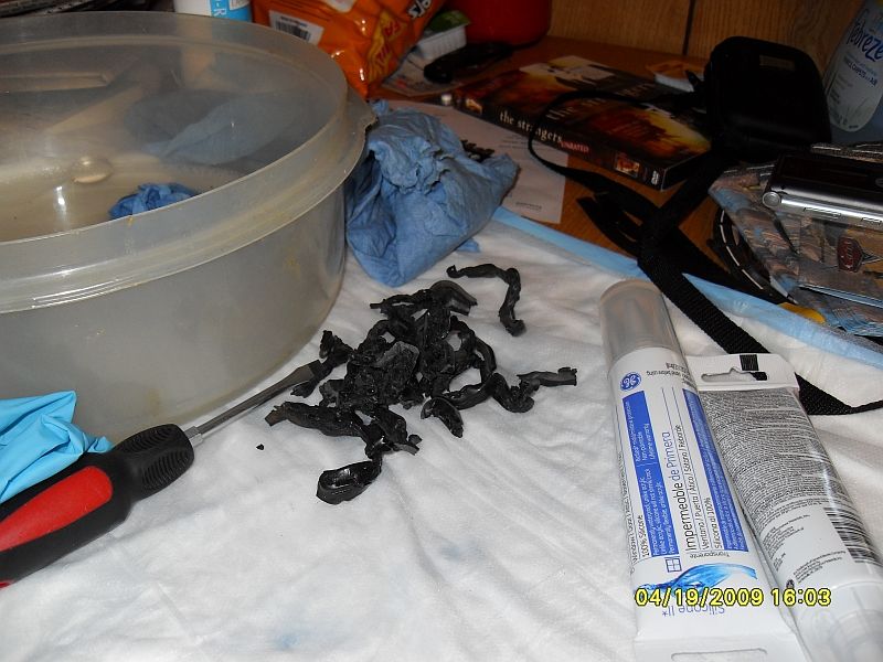 Pile of black rubber pieces next to sealant tubes and a screwdriver