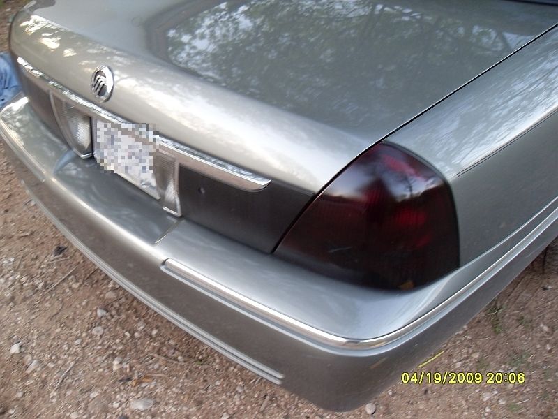 Silver car's rear bumper and taillight, with a chrome strip and a Mercury emblem