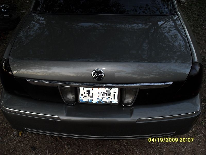 Rear of a 2004 Mercury Marquis with a chrome strip above the license plate and dark taillights