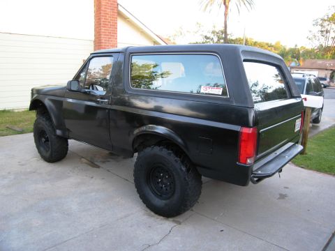 1986 Ford Bronco - This black SUV features large off-road tires and a lifted suspension, suggesting it is modified for off-road use.