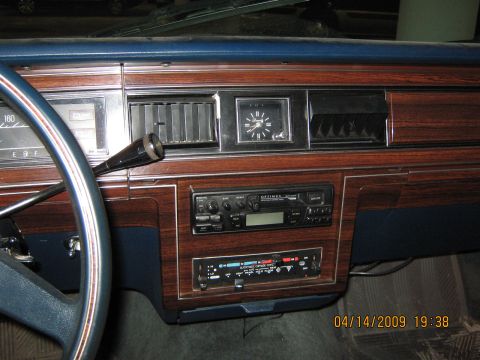 1985 Ford LTD - Close-up of a car's dashboard woodgrain accents, an analog clock, and dual radio units.