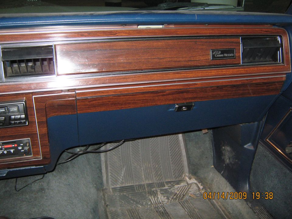 Dashboard with wood grain trim, blue upholstery, and a "Crown Victoria" badge
