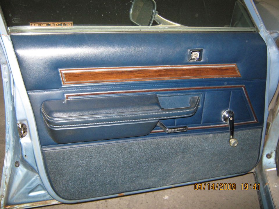 Blue vinyl door panel with woodgrain trim and chrome window crank on light blue car