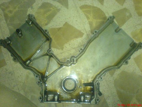 1992 Ford Crown Victoria - This is an engine timing cover, likely from a V-engine, showing signs of oil residue.