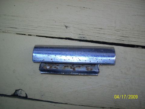 1972 Ford Ranchero - A chrome trim piece with a rusted metal bracket is shown against a weathered wooden surface.
