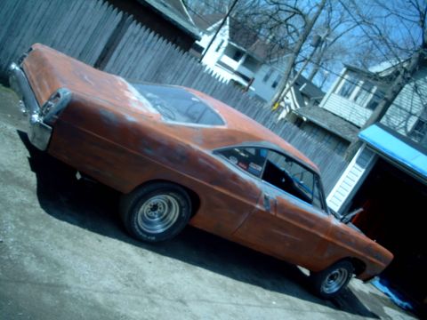 1967 Ford Galaxie - A weathered 1967 Ford Galaxie coupe sits in a driveway, showing signs of bodywork and primer.