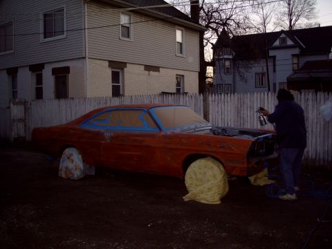 1967 Ford Galaxie - A person spray paints an orange 1967 Ford Galaxie coupe in a residential driveway.
