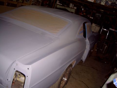 1967 Ford Galaxie - A car body, prepped for paint, sits in a dimly lit garage with its windows taped off.