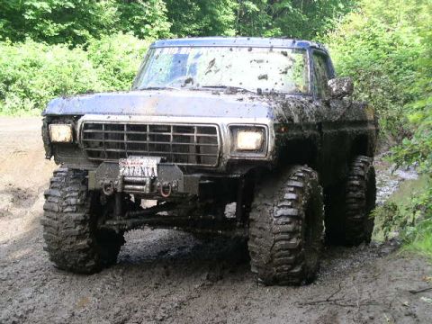 1979 Ford Bronco - A heavily mud-splattered 1979 Ford Bronco navigates a muddy trail.