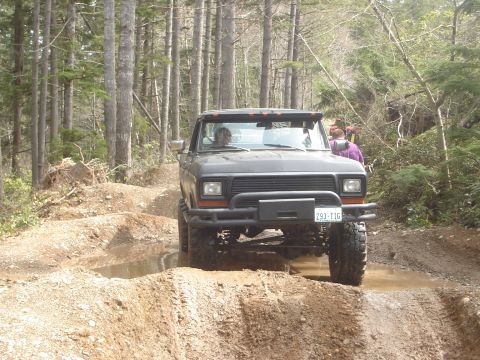 1989 Ford Bronco - A dark gray Ford Bronco navigates a muddy off-road trail.