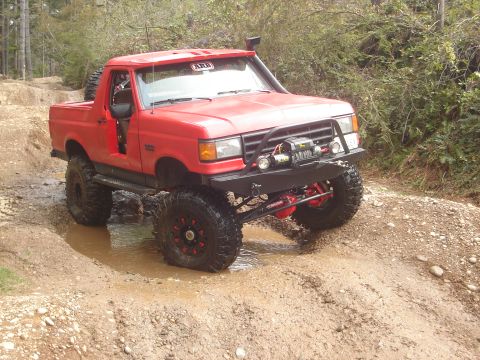 1989 Ford Bronco - 1989 Ford Bronco navigating a challenging muddy off-road course.