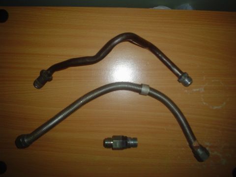 1996 Mercury Grand Marquis - Two automotive fuel lines and a connector are laid out on a wooden table.