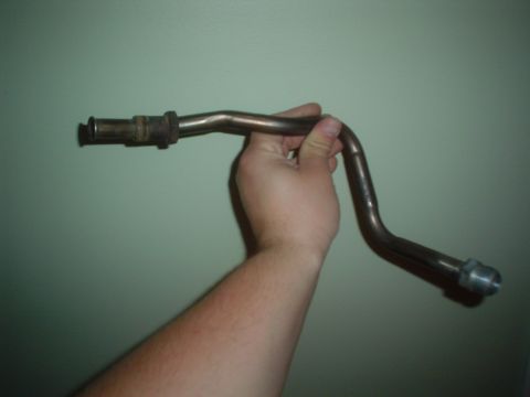 1996 Mercury Grand Marquis - A metal pipe component is held up against a plain green background.