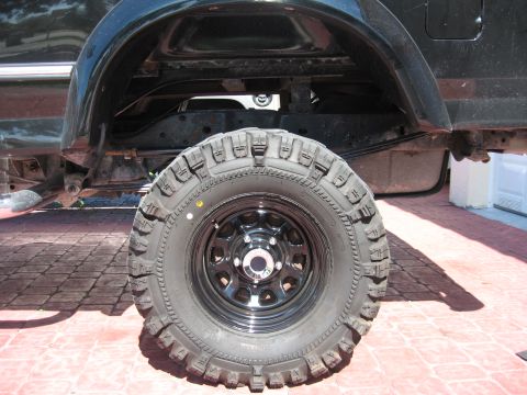 1994 Ford Bronco - Close-up of a black SUV's rear wheel and fender, revealing its suspension and tire details.