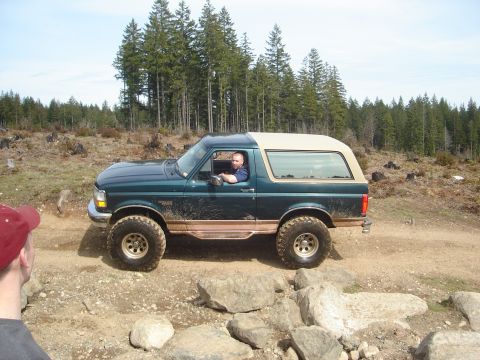 1989 Ford Bronco - 1989 Ford Bronco navigating a rocky trail in a wooded area.