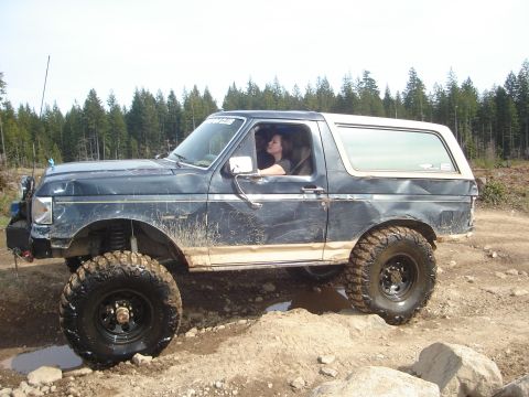 1989 Ford Bronco - A modified Ford Bronco navigates a rocky, muddy off-road course with a driver inside.