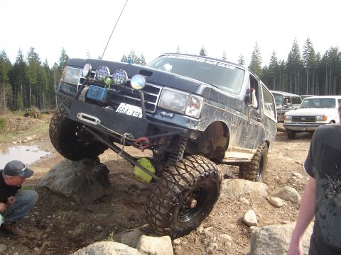 1989 Ford Bronco - A dark blue 1989 Ford Bronco navigates a rocky trail, with other vehicles visible in the background.