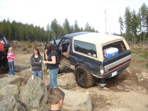 1989 Ford Bronco - A group of people and a Ford Bronco are gathered on a rocky terrain surrounded by trees.