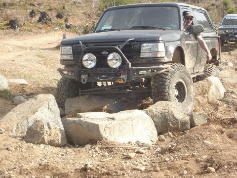 1989 Ford Bronco - This modified Ford Bronco is shown tackling a challenging off-road course with large rocks.