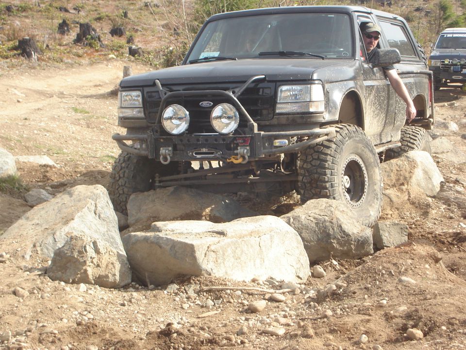 Black Ford Bronco navigating rocky terrain, front view
