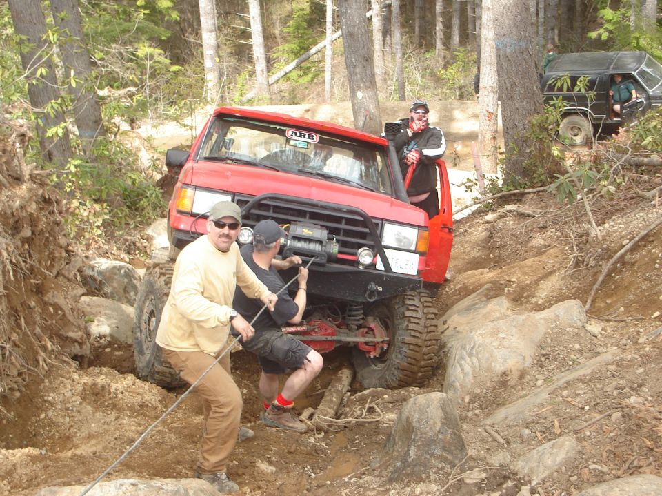 Red 1989 Ford Bronco winched on rocky terrain