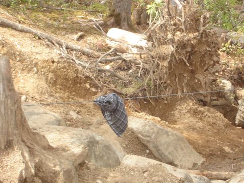 1989 Ford Bronco - A plaid shirt is suspended on a wire in a rocky, wooded area.