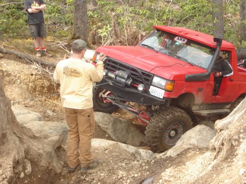 1989 Ford Bronco - Off-road pickup truck maneuvers through a challenging rocky terrain with assistance from a spotter.