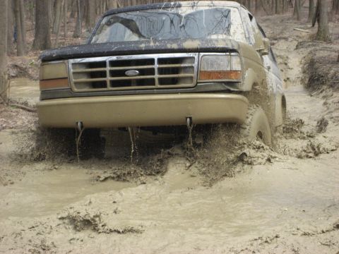 1991 Ford Bronco - Ford Bronco struggling through a muddy trail, tires deep in the muck.