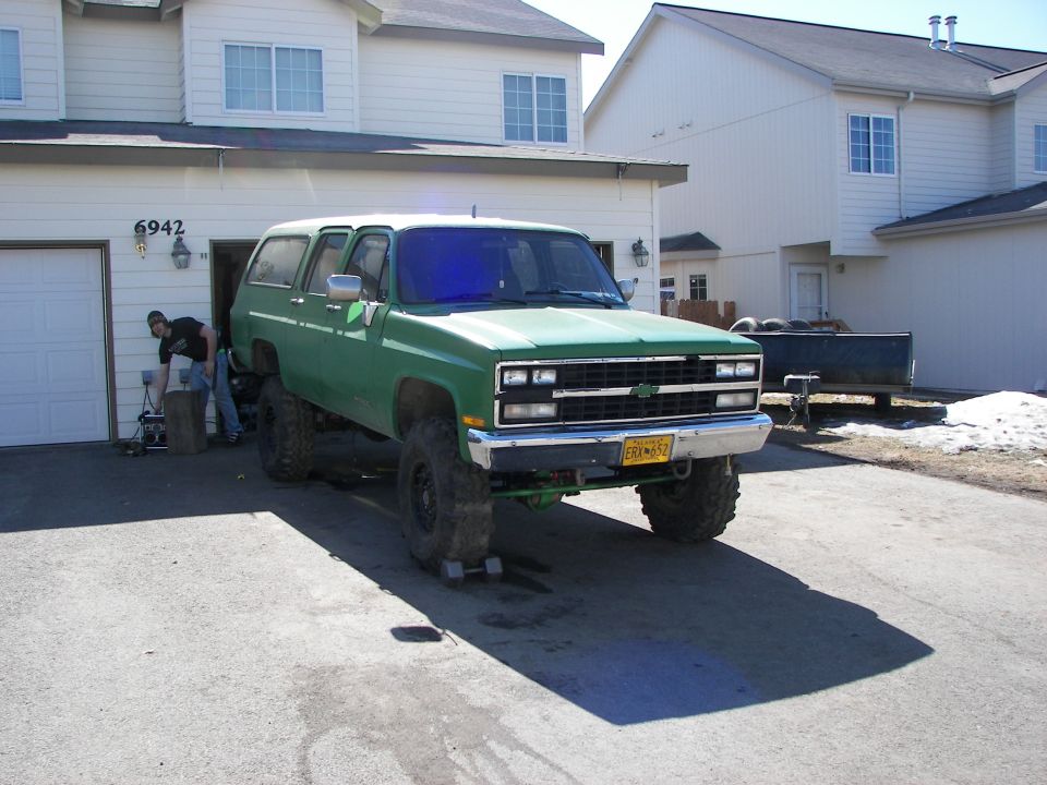 Green 1990 Chevrolet Suburban with lifted suspension and large tires