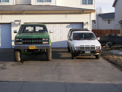 1990 Chevrolet Suburban - Two pickup trucks are parked in front of a residential garage.